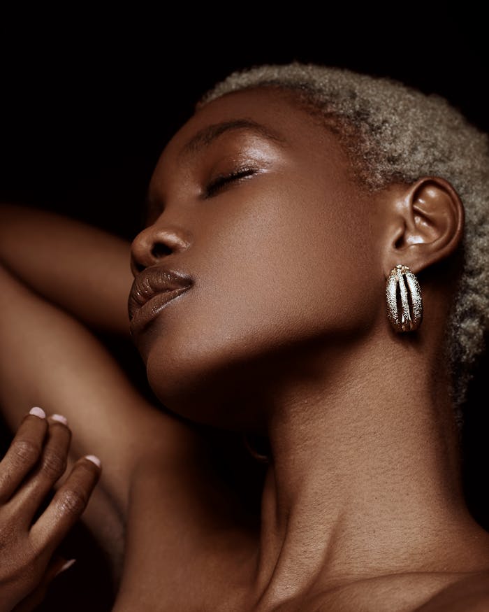 Side profile of a woman with short hair and elegant earrings, eyes softly closed.