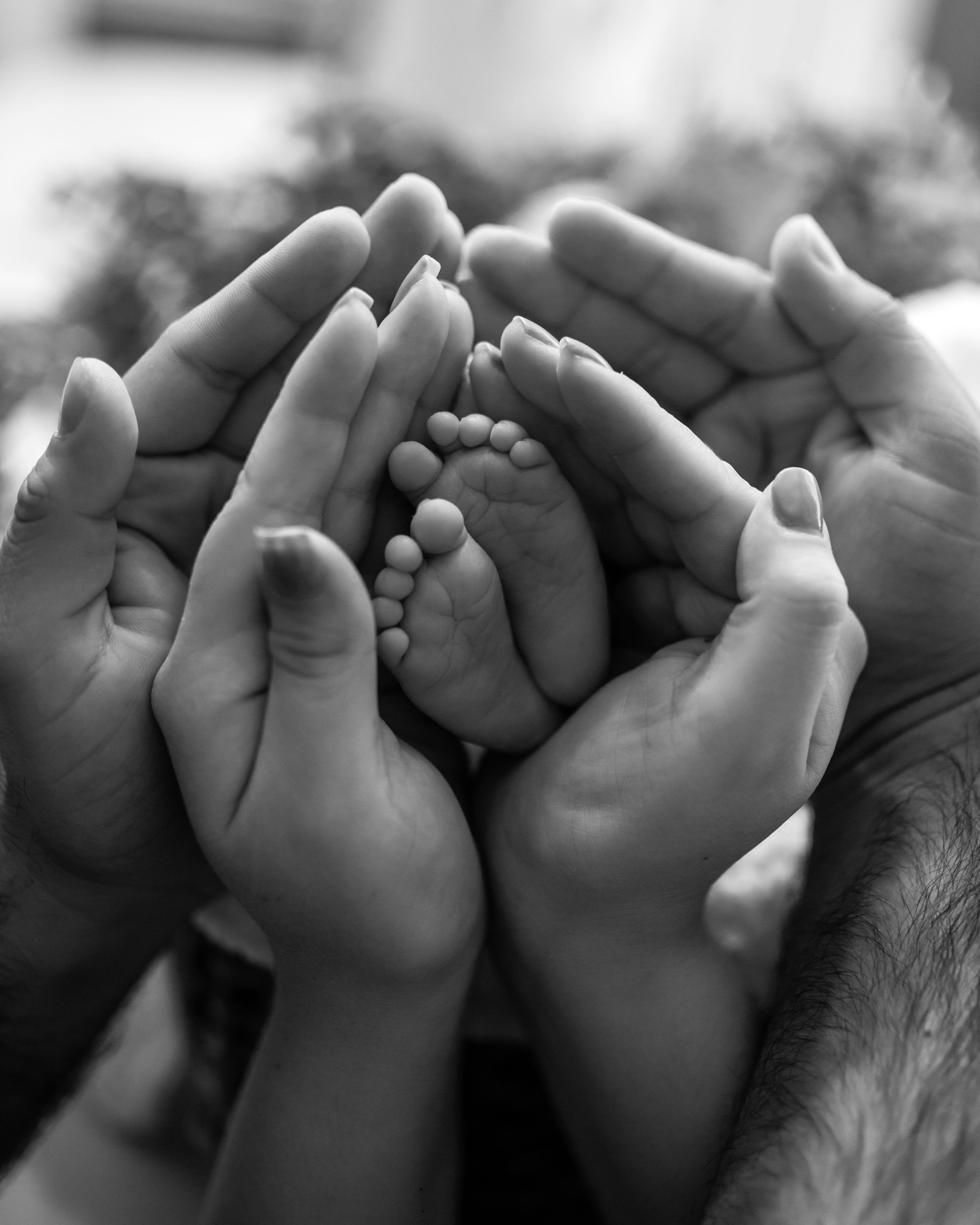 A touching black and white image capturing a family holding a baby's feet, symbolizing love and unity.