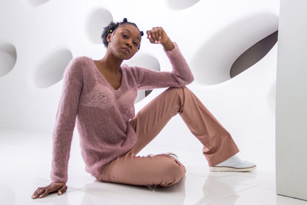 Elegant woman posing stylishly in a modern studio with geometric patterns.